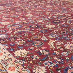North East Persian Meshed hand-knotted carpet, rich red all-over field of finely decorated with dense scrolling floral sprays and palmettes and flowering vines, enclosed by a broad border in soft pastel tones, flanked by multiple guard borders, with cotton fringe ends  