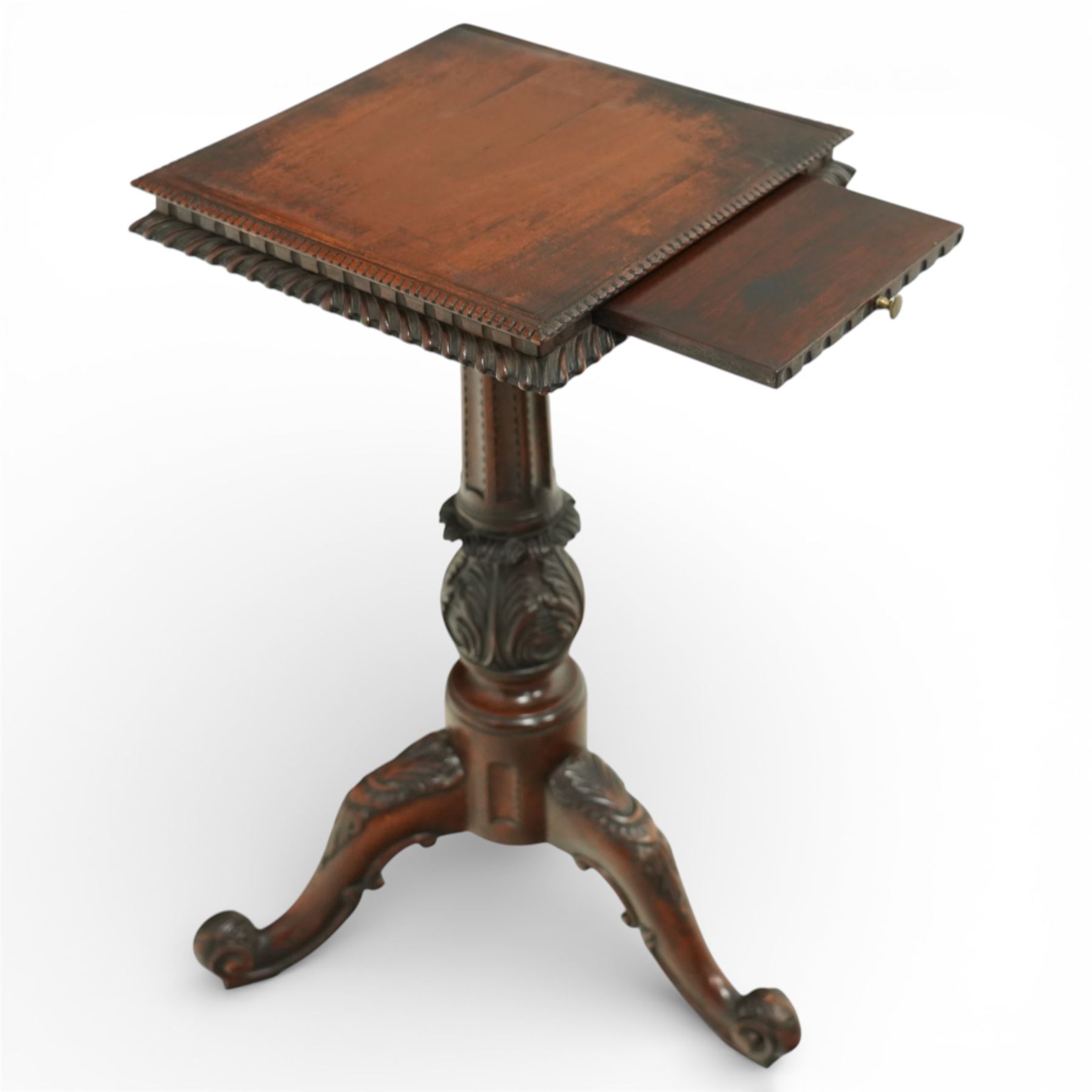 George III style carved mahogany kettle stand, the square top with gadrooned edge above a pull out slide, raised on a turned and carved baluster column issuing three carved cabriole legs terminating in scroll feet