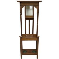 Edwardian oak hall stand, raised back with rectangular bevelled mirror plate surrounded by shelf and coat hooks, fitted with a glove box with hinged lid, over an undertier with two inset umbrella drip trays