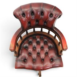 Captains swivel desk chair upholstered in oxblood leather, buttoned back and seat, shaped arm bow raised on turned spindles, five spoke base raised on castors