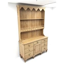 Waxed pine dresser with plate stand, projecting cornice, two shelves above six short drawers, dresser is complete with six drawers and single opening cupboard, turned supports 