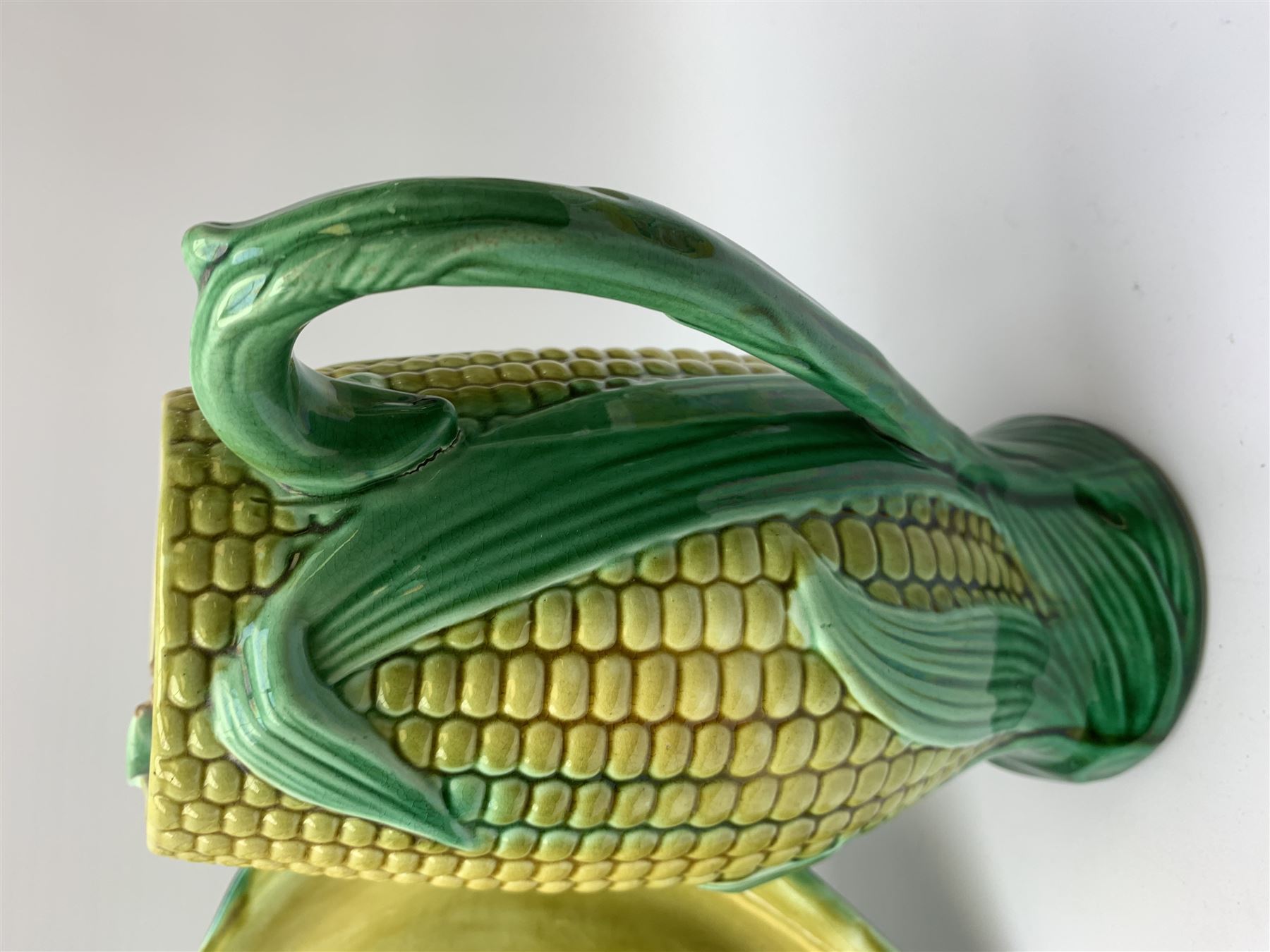 A Victorian majolica bread plate depicting corn within a woven basket, L33cm, together with a Victorian majolica jug modelled in the form of a corn cob, with registration mark beneath, H22cm. 