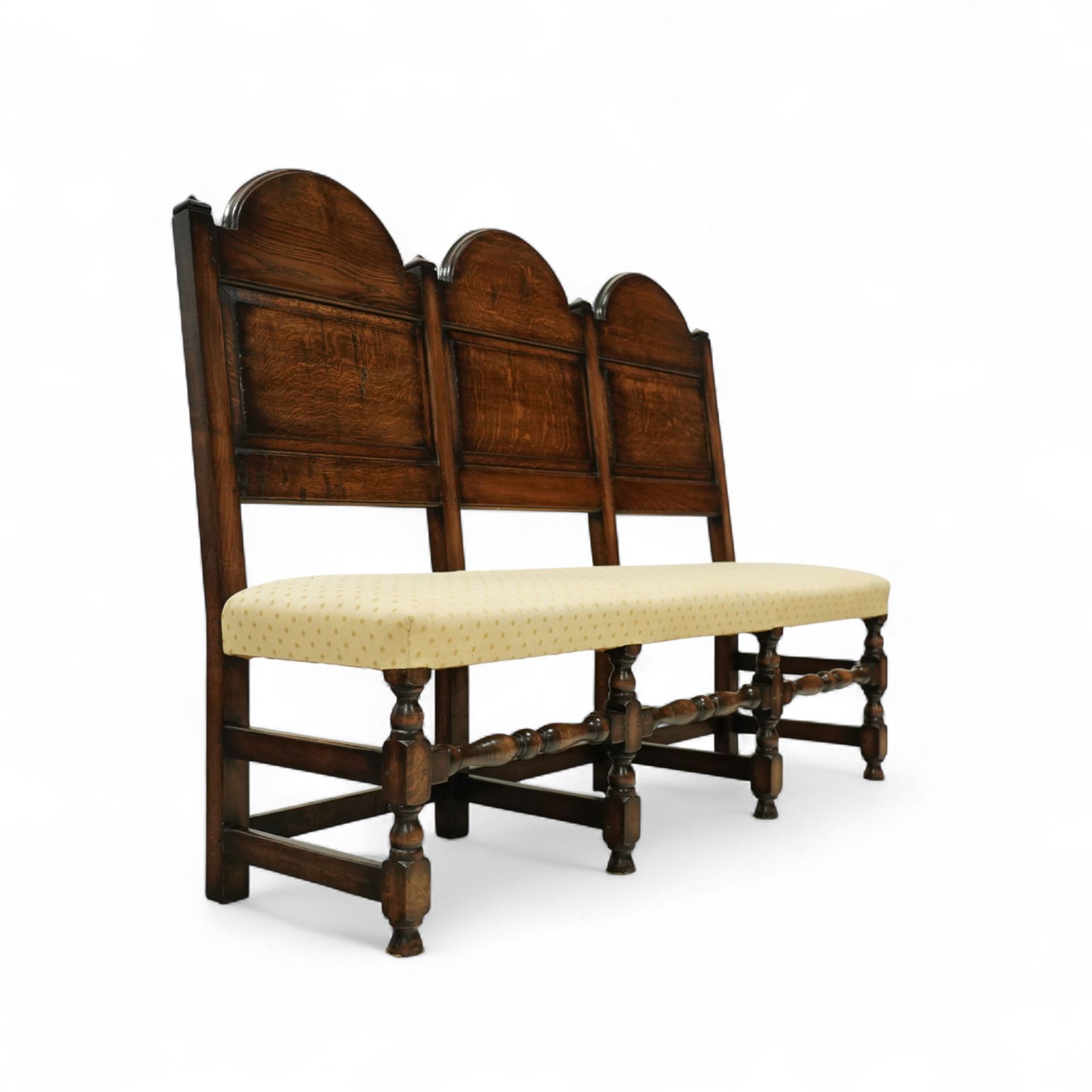 Bylaw of Ross On Wye - 17th-century design oak three-seat hall bench, triple arched panelled back, padded seat upholstered in a yellow herringbone ground fabric with star motif, raised on turned baluster legs united and turned front stretcher