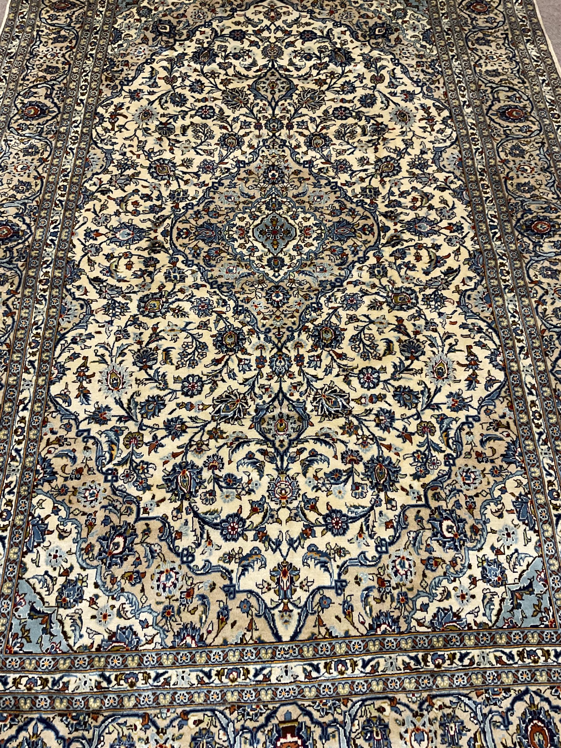 Persian Kashan ivory ground carpet, the field decorated profusely with interlacing branch and stylised plant motifs, scrolling border with overall floral design 