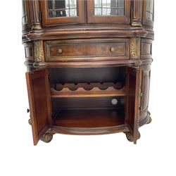  Kevin Charles American walnut demi lune display cabinet with illuminated interior, projecting cornice, two bevel edge glazed doors enclosing two adjustable shelves above single drawer and four cupboard doors with wine rack, carved scrolling supports