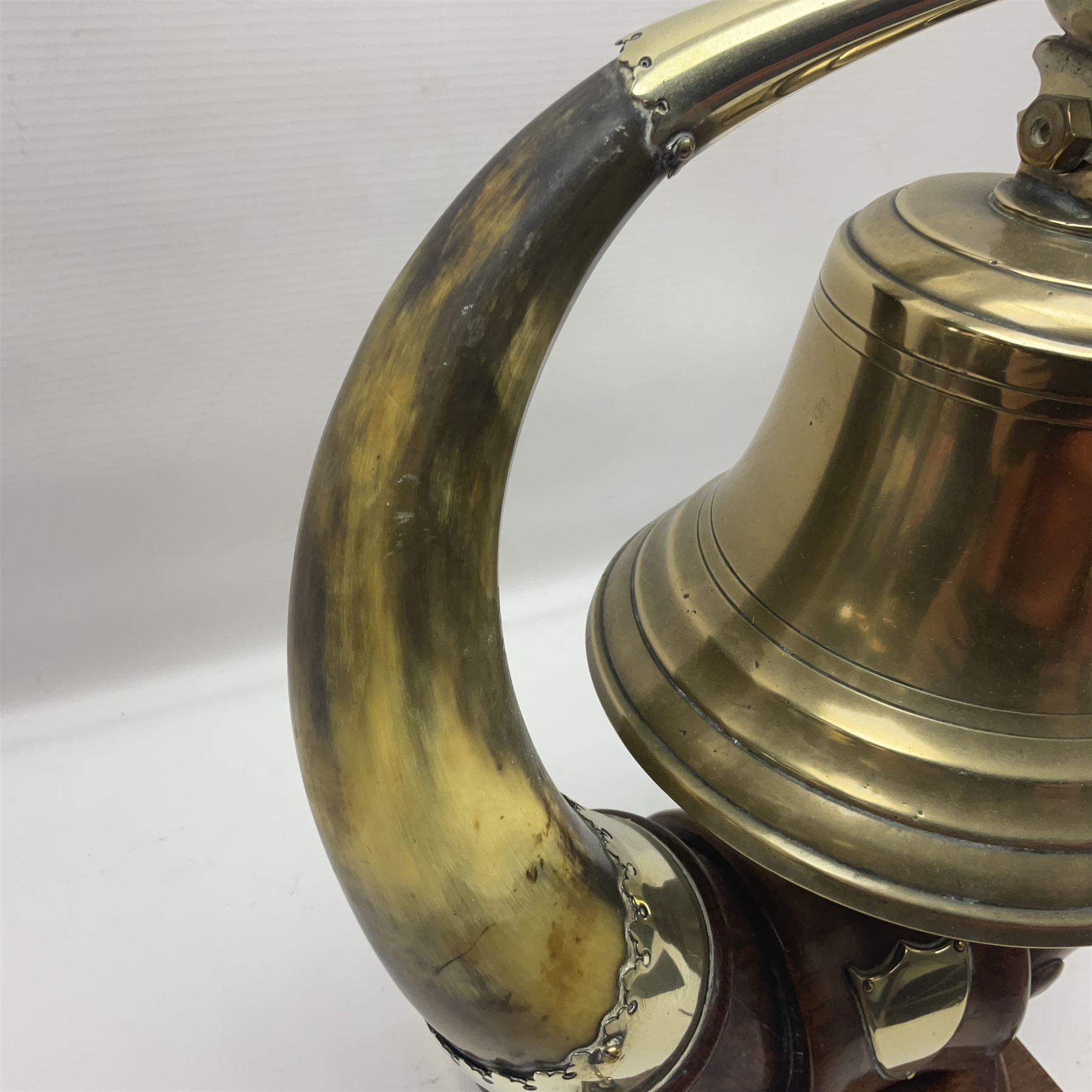 Early 20th century oak and horn dinner bell, the silvered bell suspended from a pair of cow horns, with silver plated mounts and blank shield shaped cartouche, upon square base, H37cm