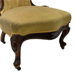 Victorian walnut nursing chair, the shaped cresting rail carved and pieced with foliate decoration, upholstered in green fabric, the apron with carved strapwork decoration, on cabriole front feet with brass castors