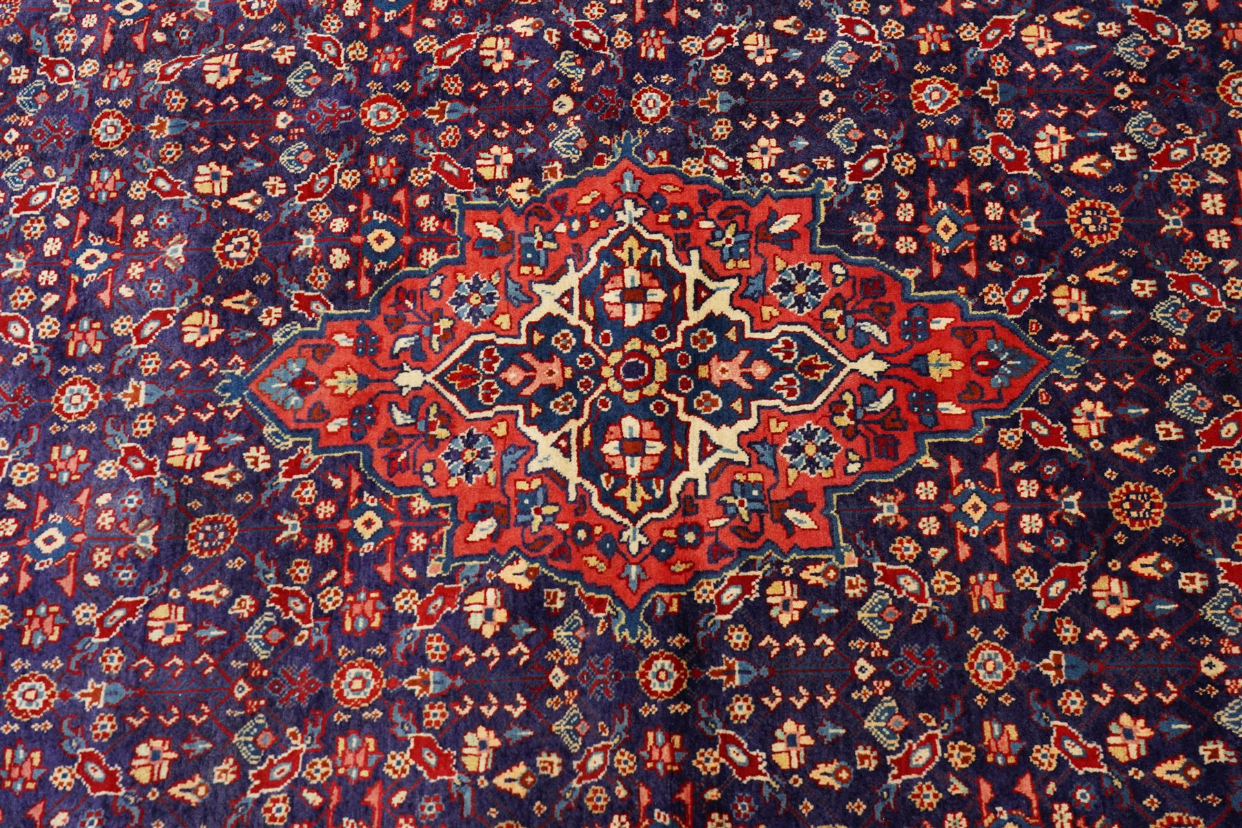 West Persian Mahal hand-knotted carpet, indigo field with central stylized angular medallion issuing an all-over Herati-inspired lattice of floral sprays, rosettes and geometric vinery in tone soft madder red, ivory and soft blue, principal border decorated with stylized palmettes, and angular vine motifs, flanked by multiple guard borders, with cotton fringe ends 