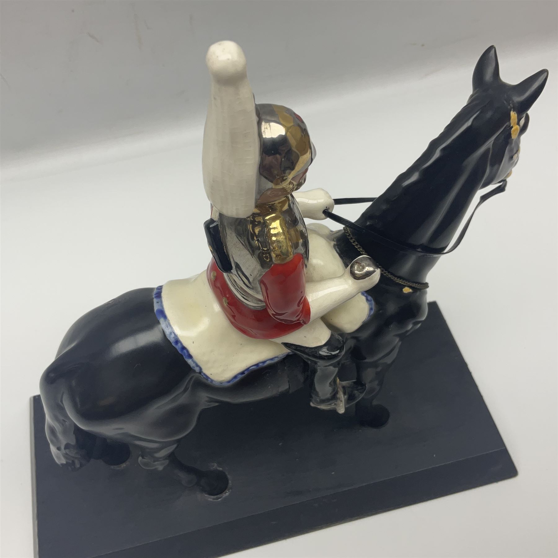 Mounted Lifeguard upon a black horse, in the style of Beswick, upon a wooden plinth, H31cm