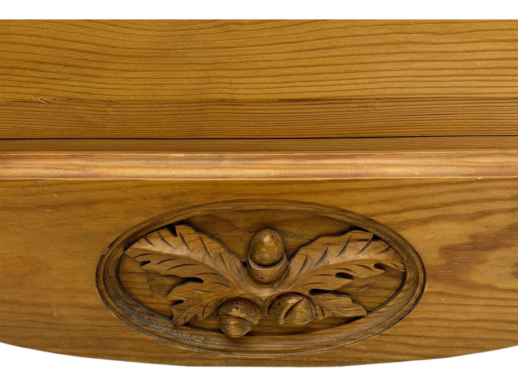 Pine chest of drawers topped with carved pediment with acorn and oak leaf motif, fitted with two short over three long drawers, standing on shaped apron base (W92, D46, H97cm); pine bedside cabinet, single drawer above paneled cupboard door enclosing open storage, shaped plinth base (W43, L32, H67cm)