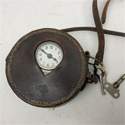Metal cased drum shaped travelling clock with grey hammered finish, French clockwork movement and stitched leather outer case with shoulder strap; bears manuscript label 'Royal Armament Research and Development Establishment - serial no.09433' D13cm overall