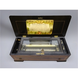 Late 19th century Swiss music box the ebonised and cross-banded case inlaid with musical trophies to the hinged lid enclosing  a glass covered movement with 28cm brass barrel playing eight airs on two steel combs with total of seventy-six teeth, original song card under lid, serial no.10985, L50cm  