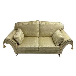 Steed Upholstery - two seat traditional shaped sofa, upholstered in cream fabric with scrolling foliate pattern, on turned front feet with brass castors, with side cushions and arm covers