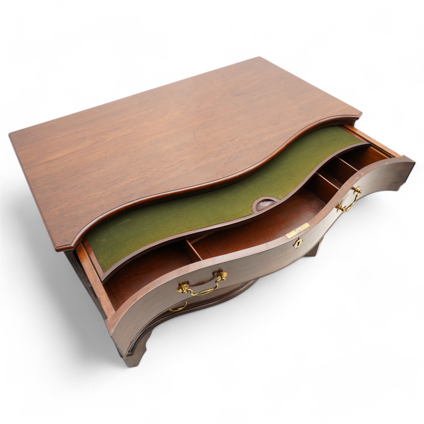 George III mahogany serpentine chest, moulded top over four cock-beaded drawers, the top drawer fitted with baize lined slide opening to reveal divisions,  enclosed by canted and fluted upright corners, the drawer fronts fitted with brass swan neck handles and circular plates with oval escutcheons, lower moulded edge over bracket feet, on lignum vitae castors