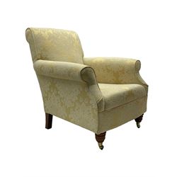 Traditionally shaped hardwood-framed armchair, rolled back and arms, upholstered in pale gold and cream damask fabric with repeating foliate pattern, on turned feet with brass cups and castors