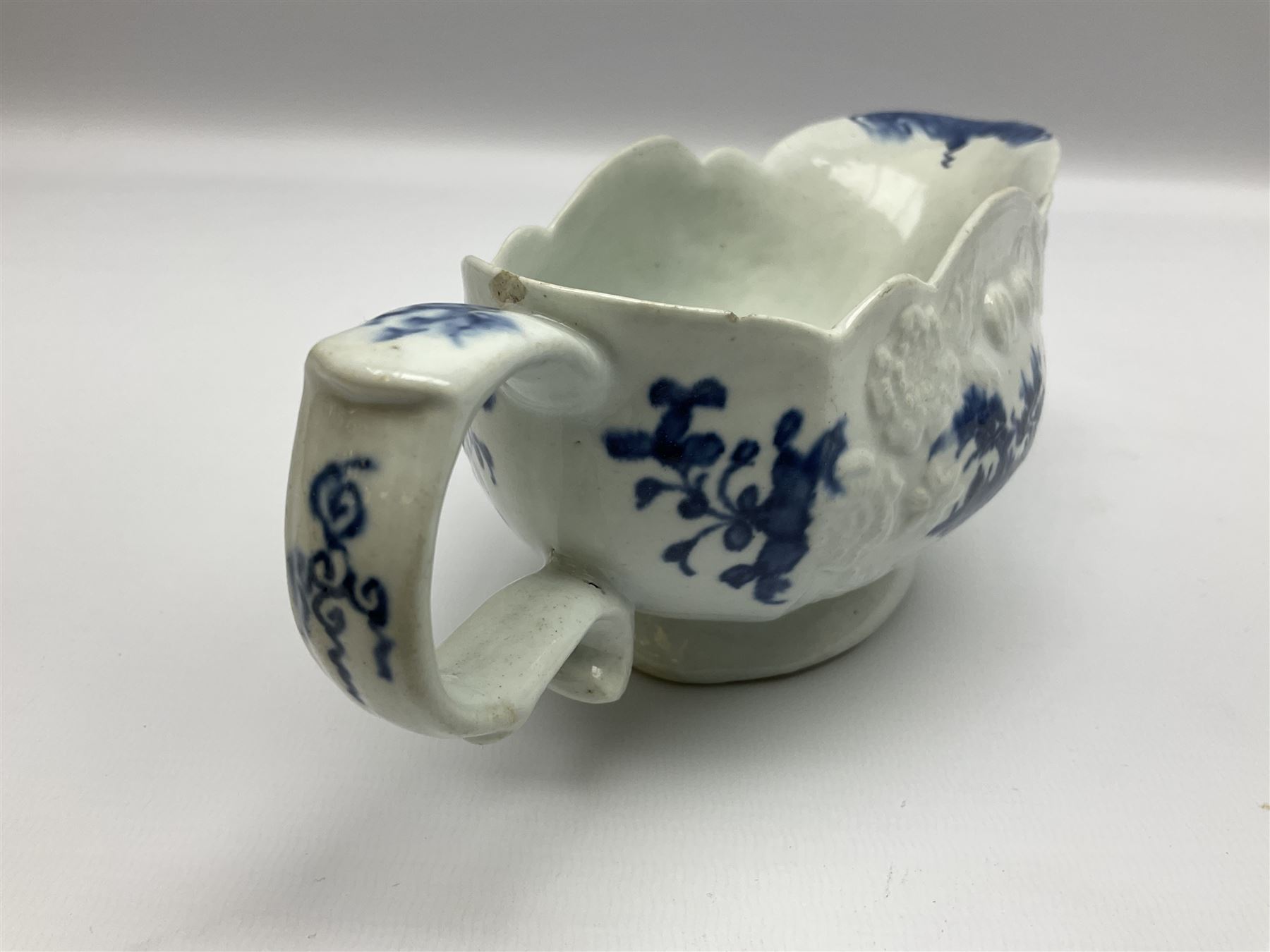 Large 18th century Lowestoft sauce boat, circa 1770, the body decorated with Hughes type floral moulding, and painted in underglaze blue with an Oriental landscape, and foliate sprigs, L23cm