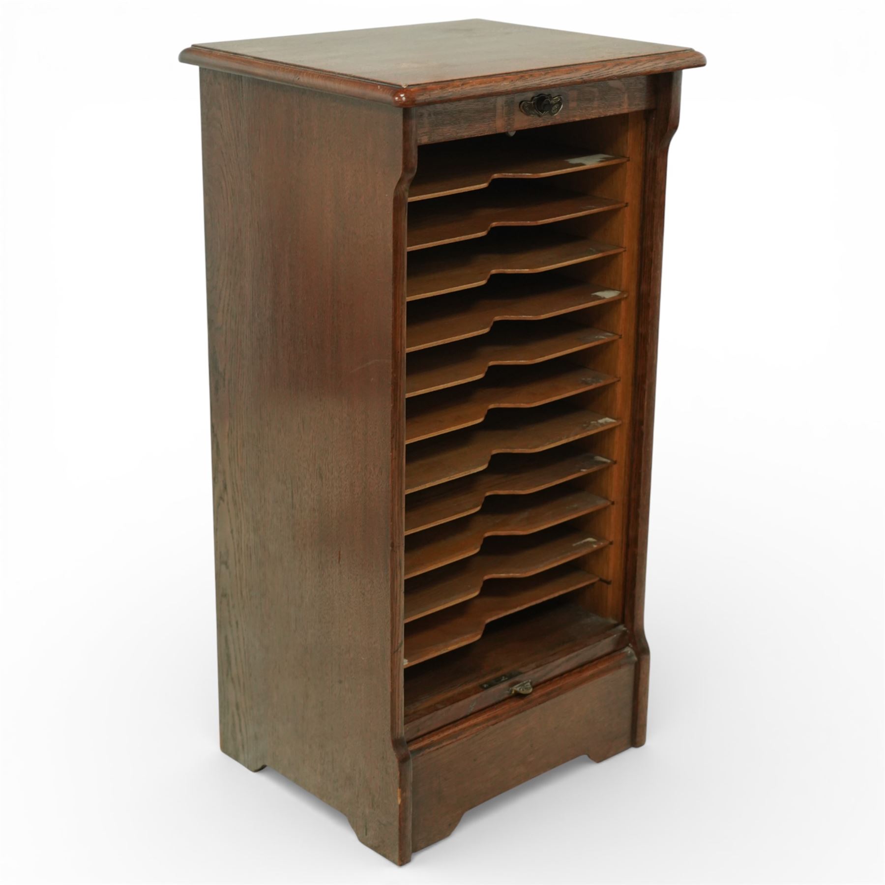Early 20th century oak filing cabinet, the rectangular top with moulded edge above a tambour shutter enclosing a fitted interior with eleven shaped filing shelves, the sides with shaped uprights, raised on a plinth base