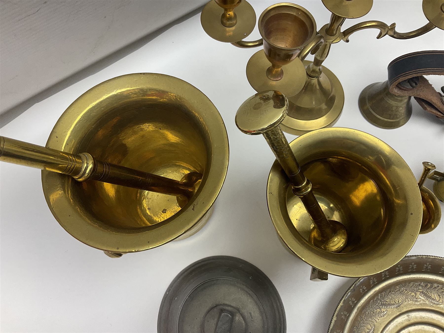 Four brass pestle and mortars, to include two miniature examples, together with other brassware including four branch candleabra, bells etc