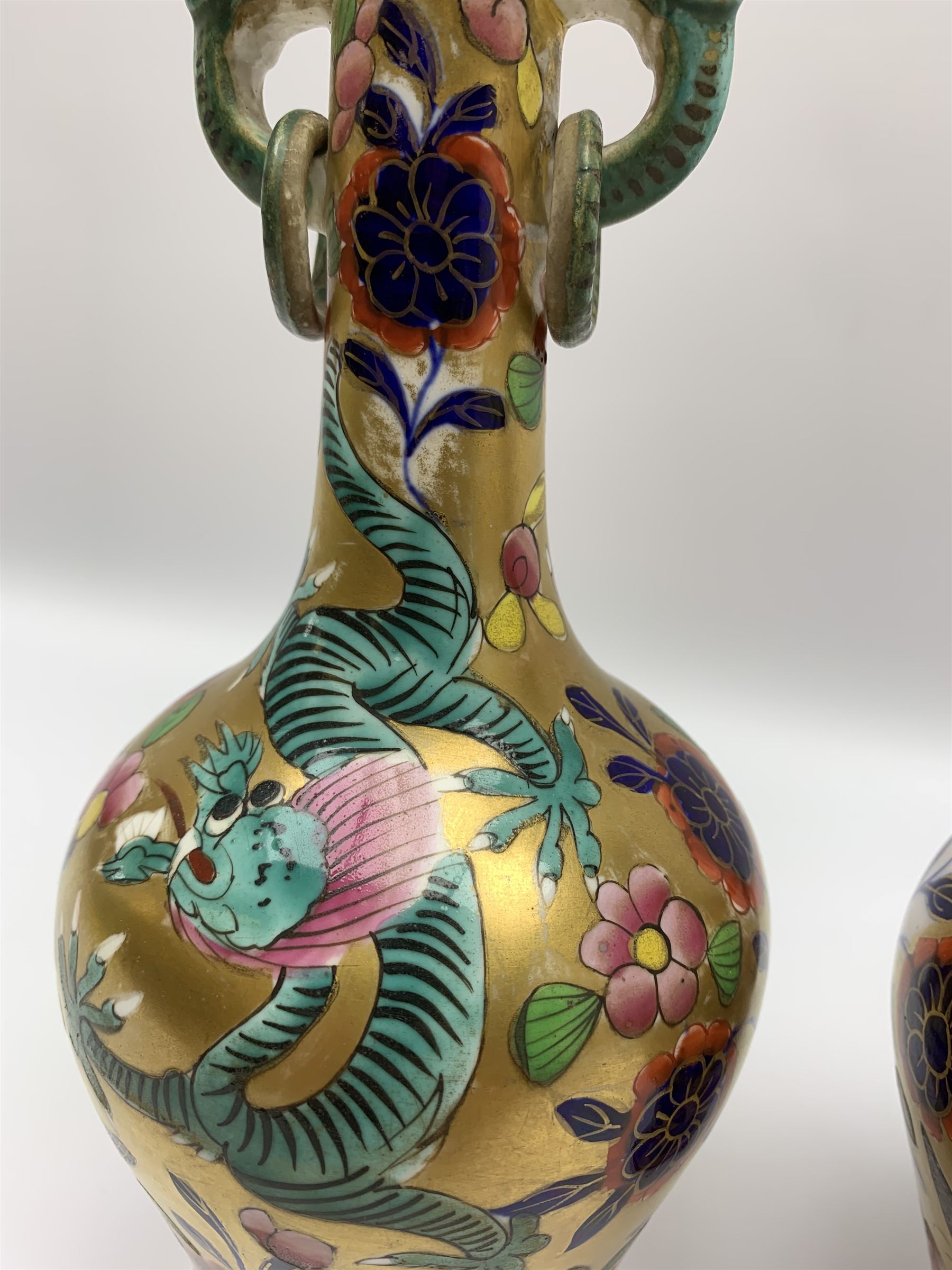 Pair of early 19th century Miles Mason vases, the baluster bodies with tall slender necks supporting twin stylised trunk handles with rings, decorated with Chinese dragons, butterflies, and blossoming flowers against a gilt ground, with spurious Chinese marks beneath in iron red, H27.5cm