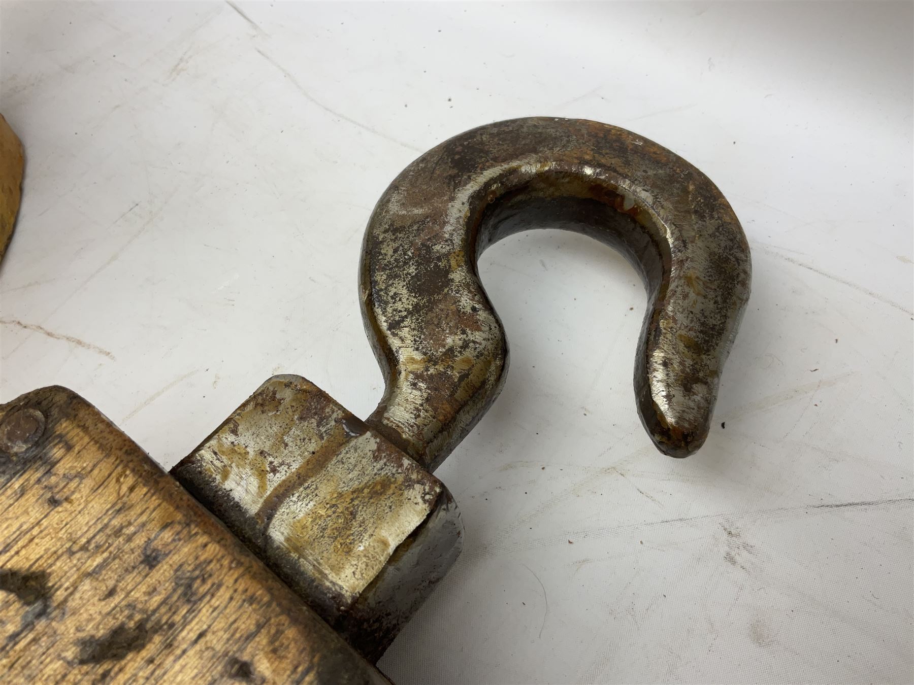 Three ship pulleys comprising wooden block double with swivel eye marked 'wooden block 240mm double rope: 22mm',  wooden block double with upset shackle and wooden block with stiff swivel hook, largest example L50cm