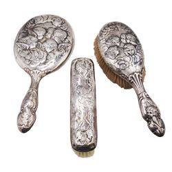 Victorian silver hand mirror, decorated in relief with putti and engraved Edith, hallmarked William Comyns & Sons, London 1899, together with a similar silver hair brush, hallmarked Birmingham 1910, maker's mark indistinct and a clothes brush, hallmarks worn and indistinct