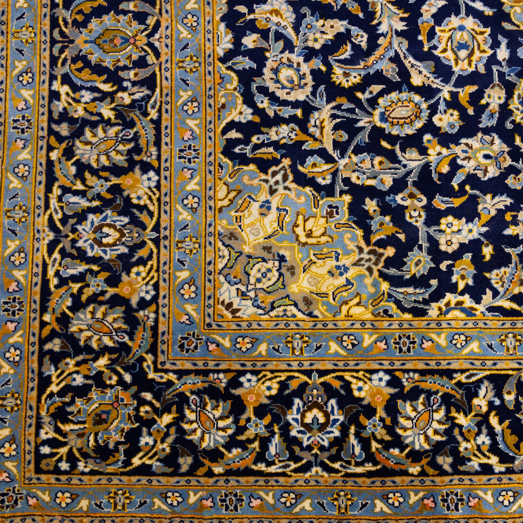 Central Persian Kashan hand-knotted rug, deep indigo field with central floral medallion surrounded by an all-over arrangement of palmettes, flowering vines, and tendrils with matching spandrels enclosed by a pale blue floral main border with multiple narrow guard stripes, with cotton fringe ends 