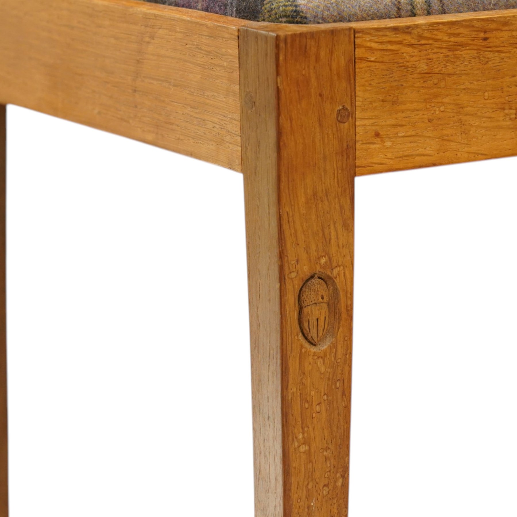 Acorn Industries - set of eight oak dining chairs, the shaped cresting rail over a fluted stick back, the drop-in seats upholstered in contrasting form with four pale mauve and four in purple tartan, raised on square supports, carved with acorn signature, by Alan Grainger, Brandsby