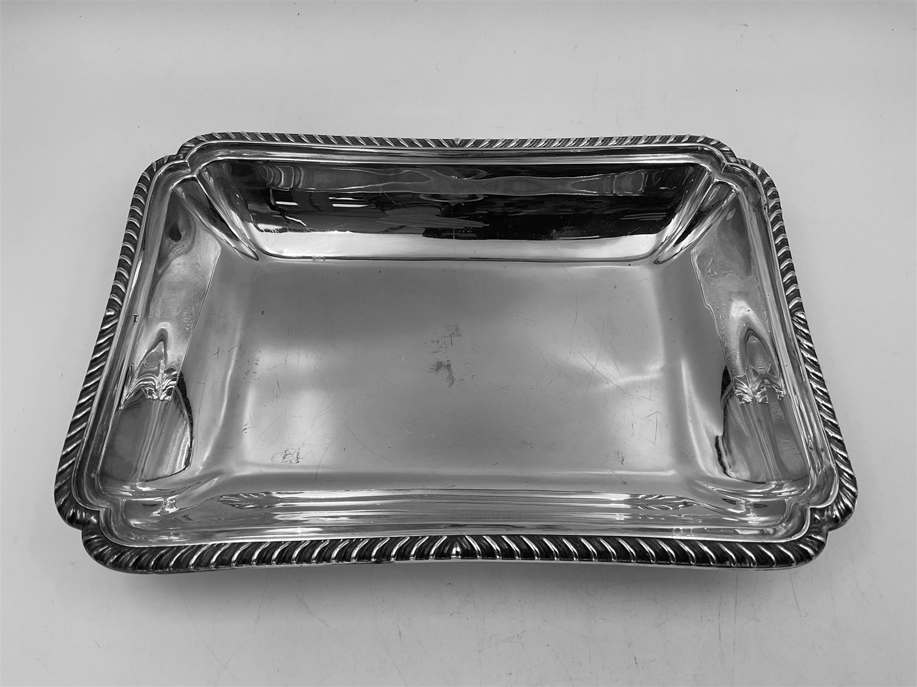 Early 20th century silver entree dish and cover, of rectangular form with shaped corners and oblique gadrooned borders to base and cover, the cover with loop 'bamboo' handle, hallmarked Thomas Bradbury & Sons Ltd, Sheffield 1930, including handle H10.5cm L24.5cm