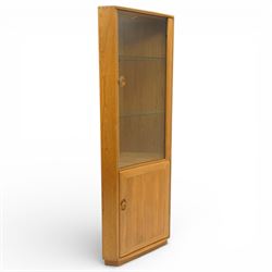 Ercol - elm corner display cabinet, Model 3856. Glazed upper section with glass door enclosing two glass shelves and interior light, above panel cupboard door, with rounded uprights and circular turned handles, on plinth base