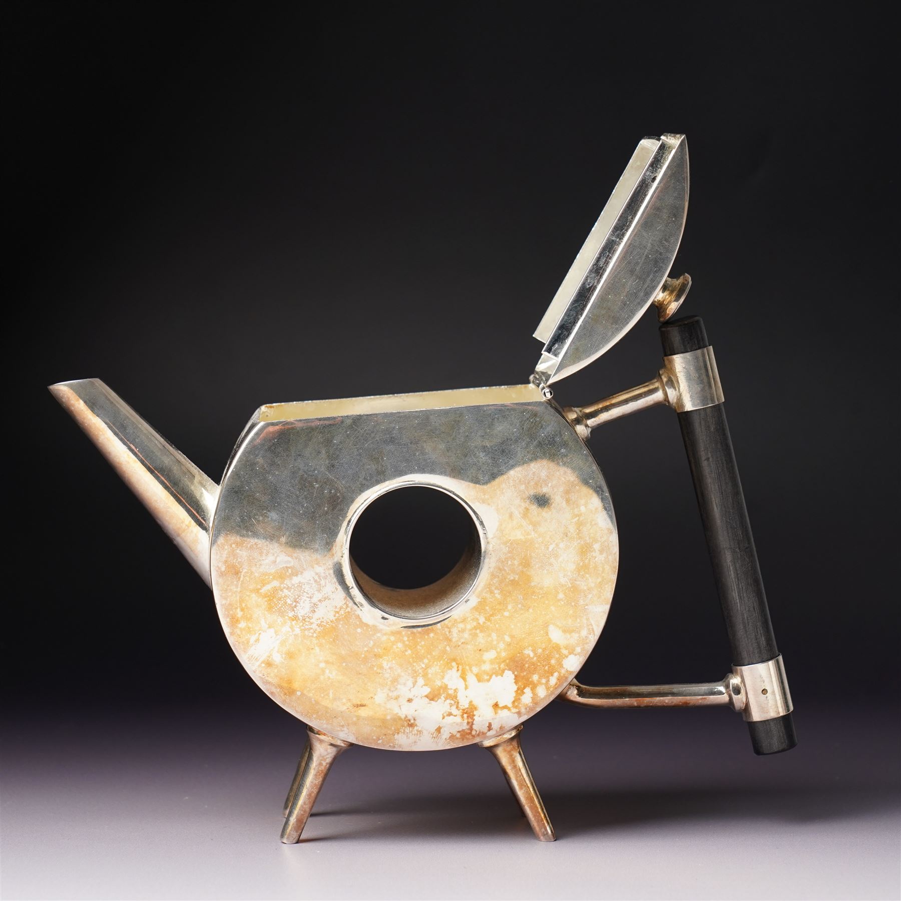 Manner of Christopher Dresser (1834-1904) - two art deco design silver plated teapots, of circular and square form with vacant centre, ebonised handles, each marked and with registration mark, max H18cm (2)