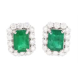 Pair of 18ct white gold emerald and diamond cluster earrings, each stud set with a single octagonal cut emerald, with round brilliant cut diamond surround, stamped, total emerald weight approx 1.30 carat, total diamond weight approx 0.70 carat