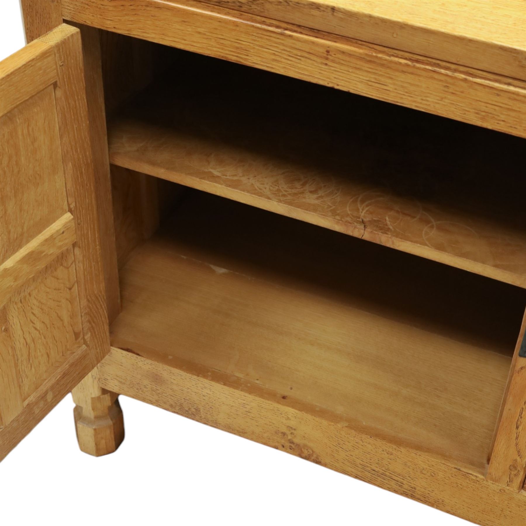 Mouseman - large adzed light oak sideboard, the rectangular top with raised galleried back, fitted with three central drawers flanked by panelled cupboards enclosing shelves, with wrought iron fittings, raised on octagonal feet, with signature carved mouse, by the workshop of Robert Thompson, Kilburn