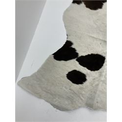 Dark brown and white patterned cow hide rug, L183cm W140cm.