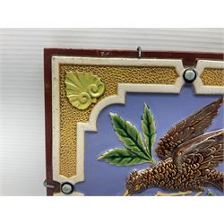 19th century Minton & Co majolica tile, decorated in relief with a bird upon a fruiting branch against a blue ground, with textured ochre border and anthemion to each corner, impressed mark verso, H19.7cm
