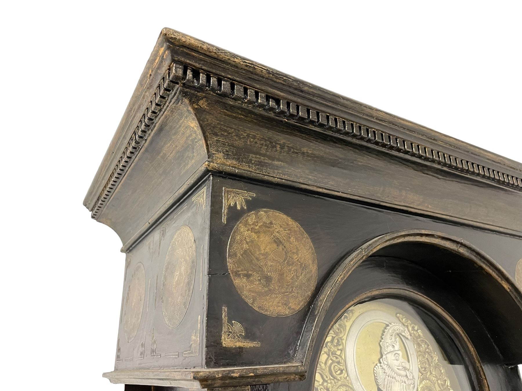 James Bowra of Sevenoaks Kent - 18th century 8-day ebonised longcase clock with gilt decoration c1740, with a flat top, dentil moulding beneath and shaped back splats, break arch hood door flanked by plain pilasters with wooden capitals, long trunk with a curved topped door, on a square plinth with canted corners and raised on a moulded base, brass dial with cast spandrels and a silvered 'Punch' automata to the arch, matted dial centre with seconds ring and date aperture, silvered chapter ring with Roman numerals, five minute Arabics, minute and quarter hour tracks, with matching steel hands and silvered makers name plate, rack striking movement with a recoil anchor escapement, striking the hours on a bell. With weights and pendulum.