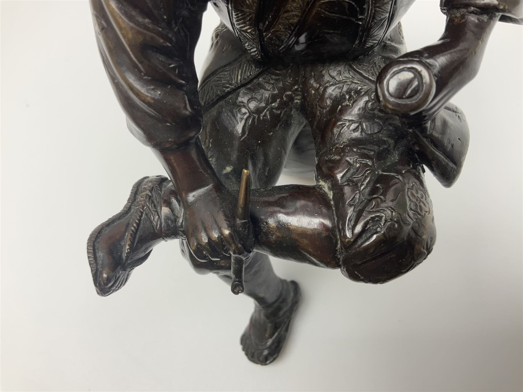 Oriental bronze figure of a gentleman, modelled seated upon barrel with a pipe in one hand and a flask in the other, H21cm