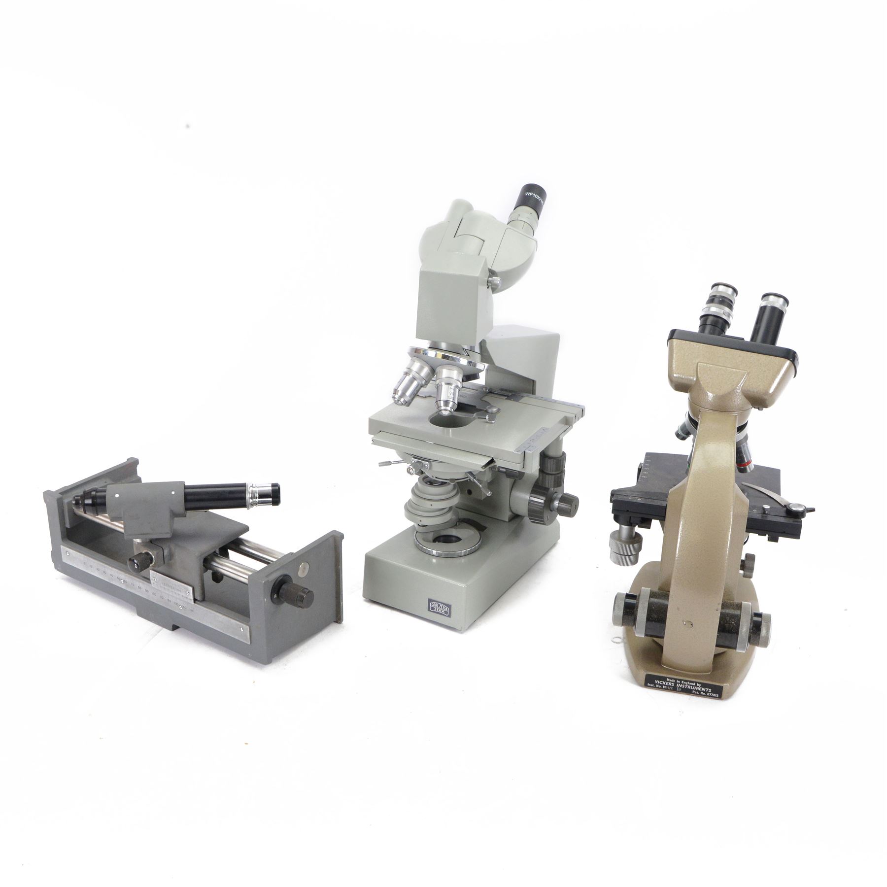 Three microscopes, including Griffin Student Vernier Microscope, Vickers Instruments binocular microscope with Leitz Wetzlar Periplan 10x lenses, and a Carl Zeiss Jena binocular microscope in a wooden Olympus Tokyo box