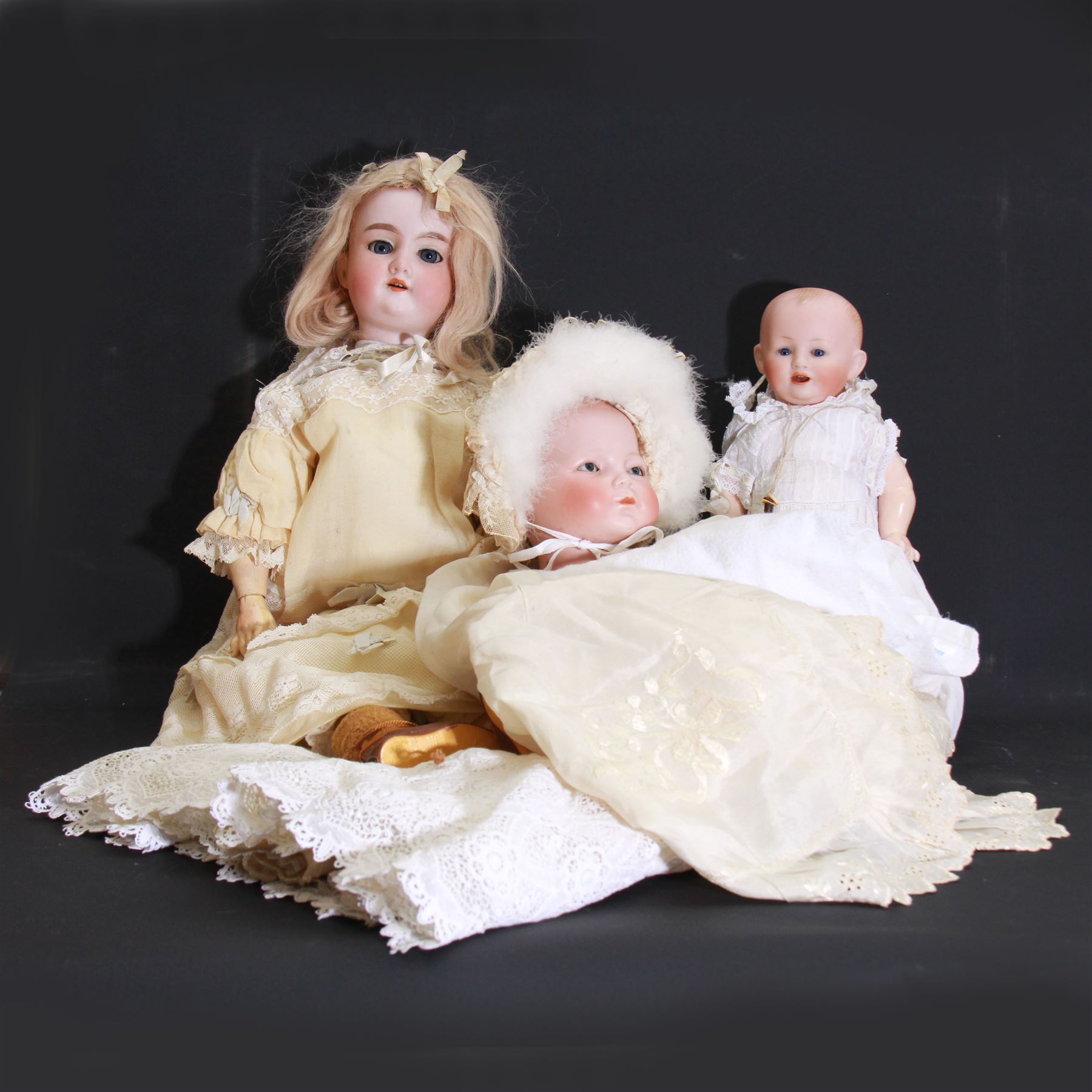 Two German bisque head dolls, to include a Franz Schmidt example with blue glass eyes and an Armand Marseille 590 example with applied hair, together with a Schoenau & Hoffmeister bisque doll's head, pair of doll's hands and a collection of clothing