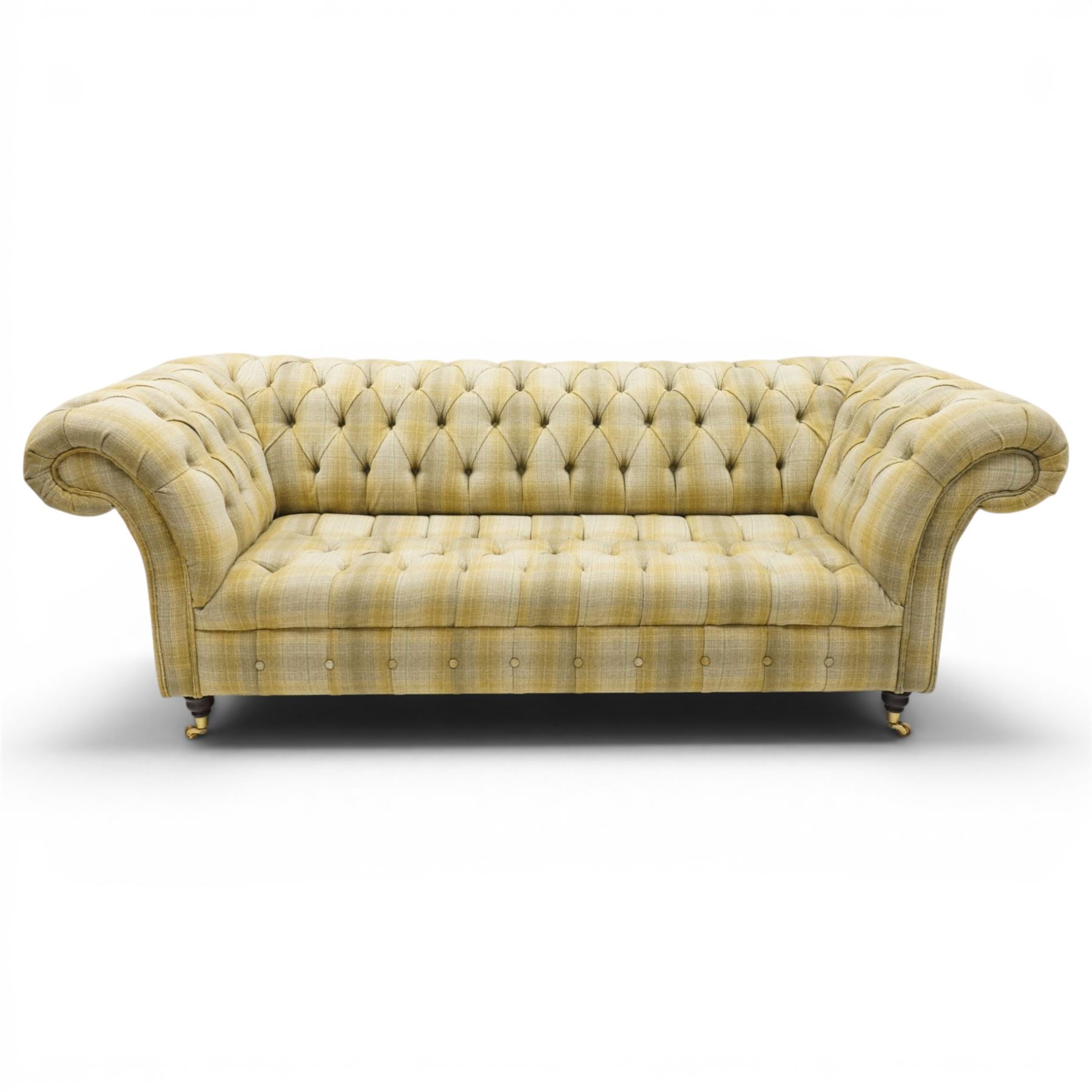 Late 20th century Chesterfield style two seat sofa, upholstered in muted green and yellow tartan fabric with buttoned back, arms and seat, on turned front supports with brass castors