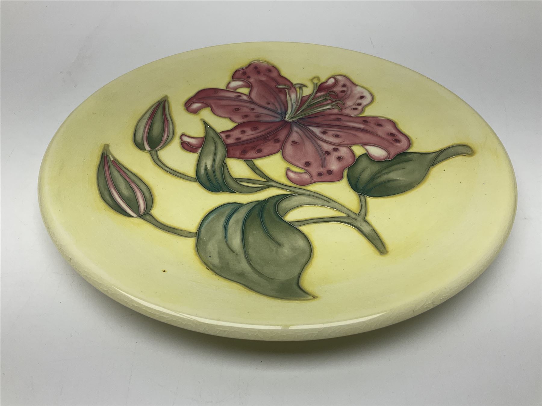Moorcroft Tiger Lily pattern plate on a yellow ground, with painted and impressed mark beneath, D26cm