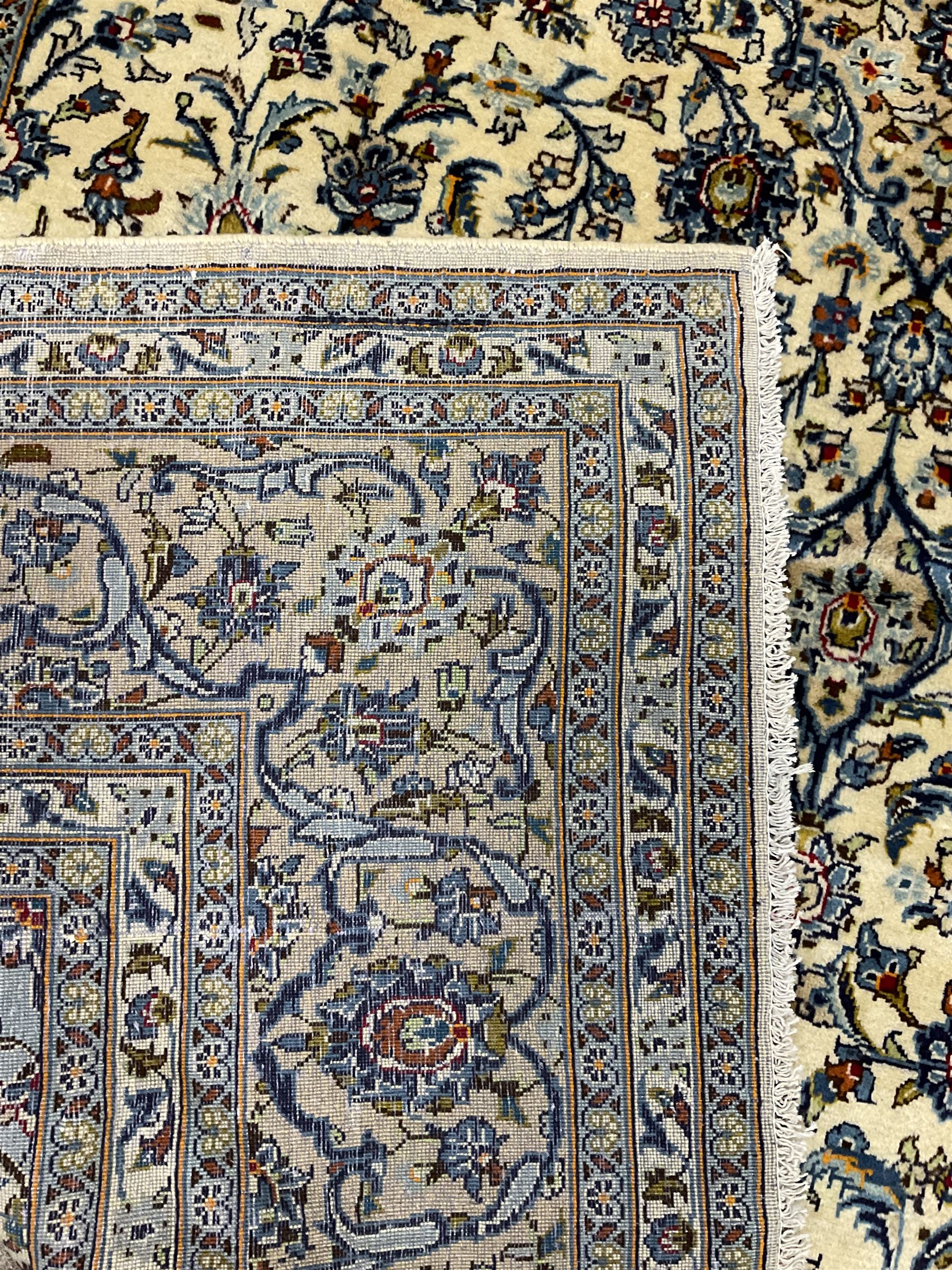 Persian Kashan ivory ground carpet, the field decorated profusely with interlacing branch and stylised plant motifs, scrolling border with overall floral design 