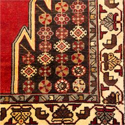 West Persian Mazlaghan hand-knotted rug, madder red field with central stepped lozenge medallion with pendant motifs flanked by angular serrated spandrels filled with small geometric devices, enclosed within multiple borders featuring stylized floral and geometric motifs, with cotton fringe ends 