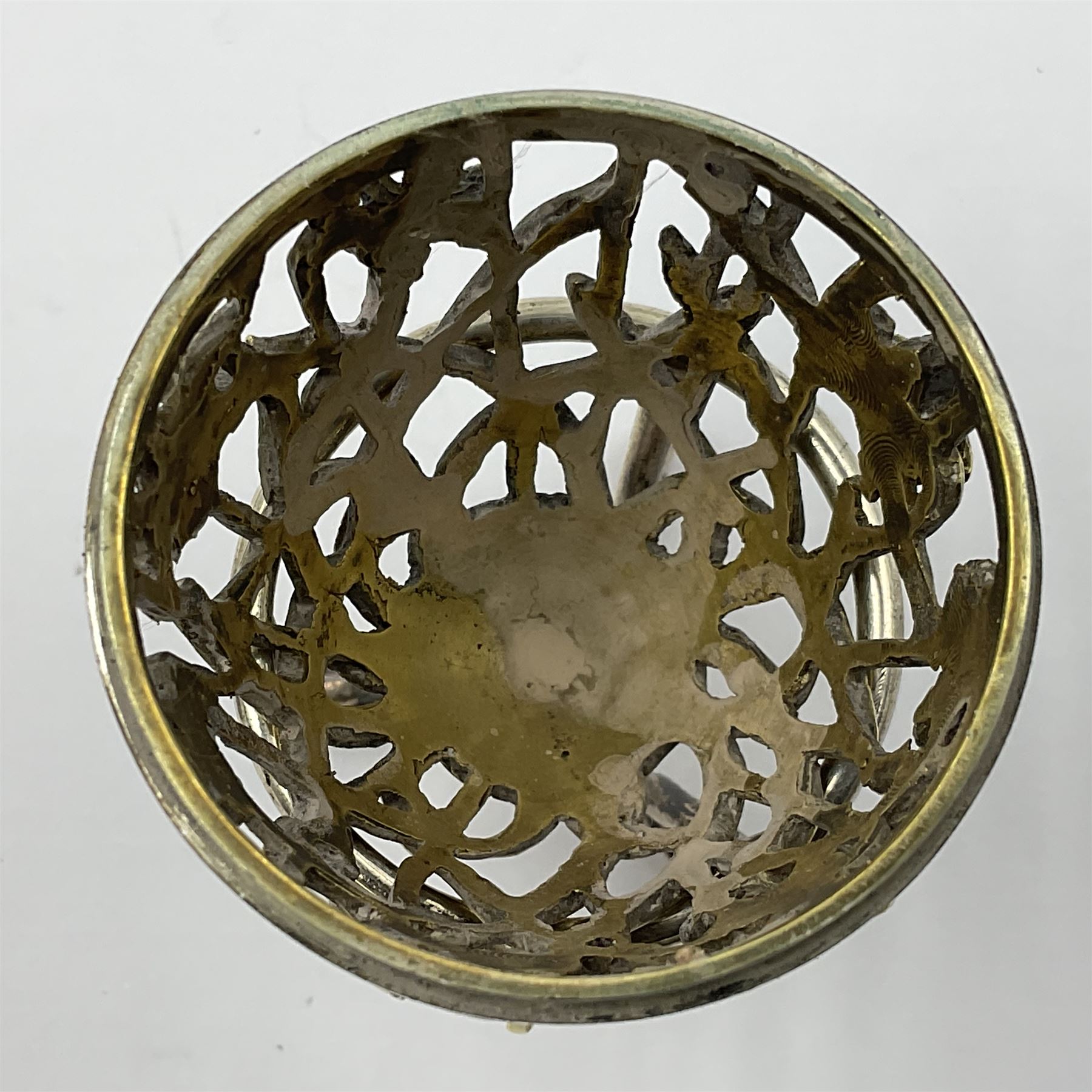 Modern silver limited edition Easter egg, no. 70/500, the gilt openwork body decorated with daffodils and detachable cover with pierced circular panel set with a single faceted blue stone, opening to reveal a gilt interior, upon silver stand with three scrolling pad feet, each hallmarked St James House Company, London 1980, height including stand 8cm