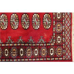Afghan Bokhara crimson ground carpet, the field decorated with eight Gul motifs with surrounding geometric woven guard bands