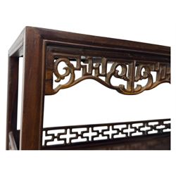 Early 20th century Chinese hardwood display étagère bookcase, the rectangular open tiered frame with pierced frieze and geometric openwork gallery to each shelf, fitted with two short drawers carved with stylised lotus motifs, supported on square uprights with pierced apron and integral gallery rails