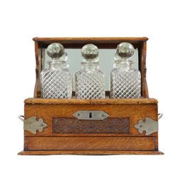 Victorian brass mounted oak tantalus, containing a set of three decanters, fitted with a g...