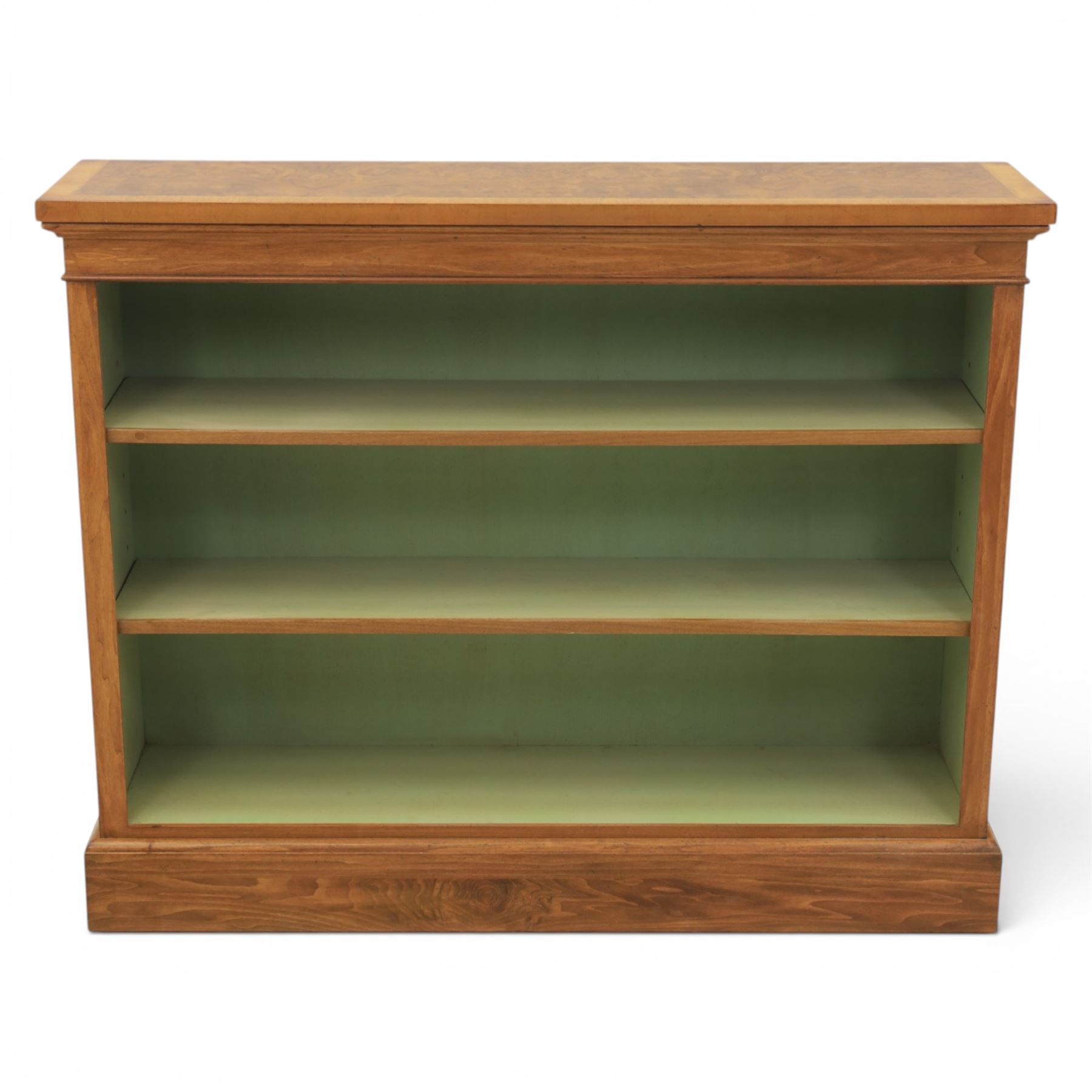 Traditional walnut small bookcase, with projecting cornice above a green painted interior, adjustable shelving, on a moulded plinth base