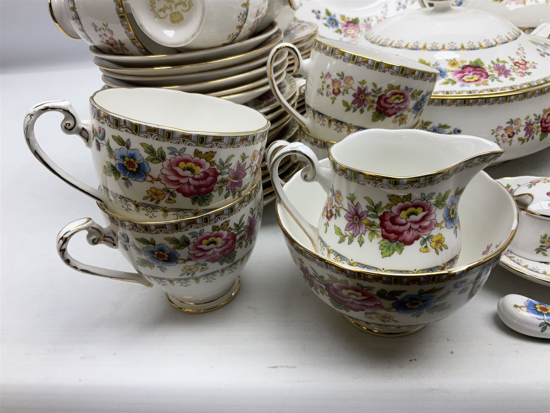 Extensive Royal Grafton Malvern pattern tea and dinner wares, comprising twelve dinner plates, six smaller plates, coffee pot, two teapots, two cake plates, eight teacups and ten saucers, six coffee cups and six saucers, two open sucriers, twin handled lidded sucrier, jug, lidded mustard pot and condiment jar, lidded tureen, two circular twin handled vegetable tureens, sauce boat and stand, oval and circular serving plates, salt and pepper shakers, breakfast cup and two saucers, further large cup and saucer, eighteen tea plates of various shapes, six side plates, six cereal bowls and six further bowls, shell dish and dish of square form, fork and knife, together with a hallmarked silver condiment spoon