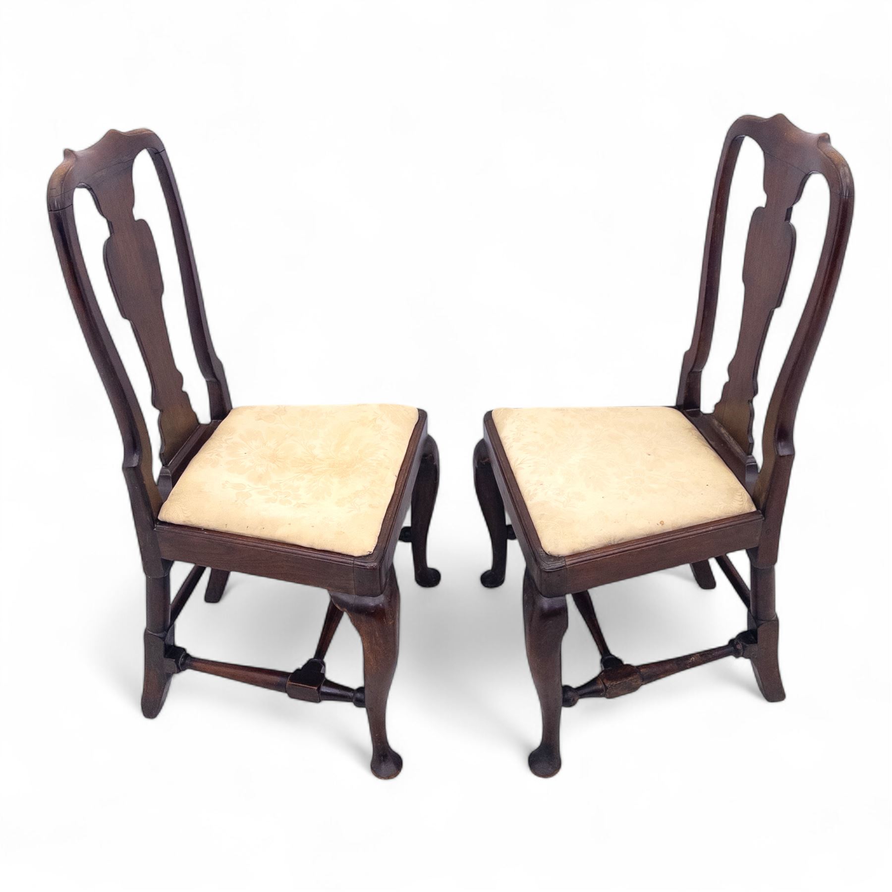 Pair of early 18th century walnut side chairs, vase-shaped splats beneath shaped top rails, drop-in seats upholstered in floral damask, on cabriole front legs terminating in pad feet, united by turned stretchers