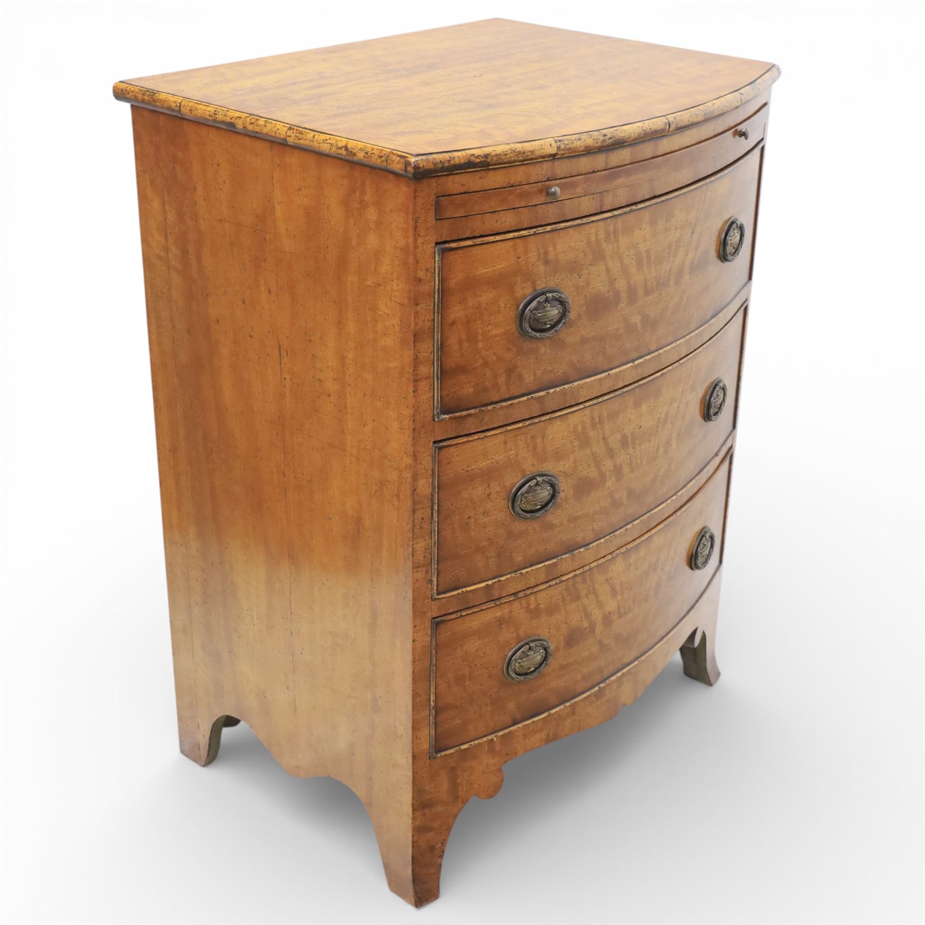 Georgian design bow front chest in figured walnut veneers, with moulded top over a pull-out brushing slide and three long drawers fitted with oval brass drop handles, raised upon swept bracket feet